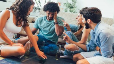 Group of friends laughing and playing a fun game of Truth or Dare, highlighting unique Truth or Dare questions to ask your friends during a social gathering.