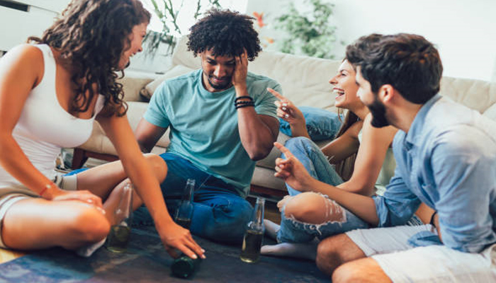 Group of friends laughing and playing a fun game of Truth or Dare, highlighting unique Truth or Dare questions to ask your friends during a social gathering.