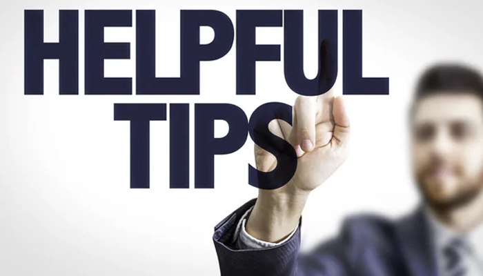 A man in a suit pointing at the bold text "HELPFUL TIPS" on a transparent screen, emphasizing guidance and advice.