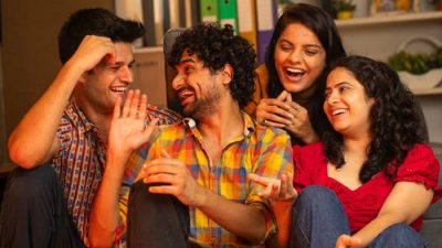 A group of four young friends laughing and enjoying a fun conversation indoors, creating a joyful and relaxed atmosphere.