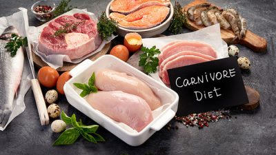 A variety of raw meats, including chicken breasts, steaks, fish, and shrimp, with a small sign reading Carnivore Diet.
