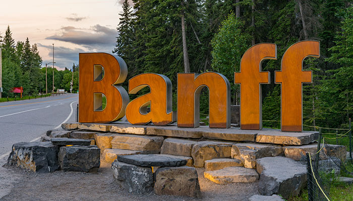 Banff sign surrounded by forest at sunset — entrance to Banff National Park, Alberta, one of the best places to visit in Canada.