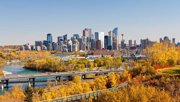Calgary skyline surrounded by golden autumn trees and Bow River — a vibrant Alberta city near the Rocky Mountains.