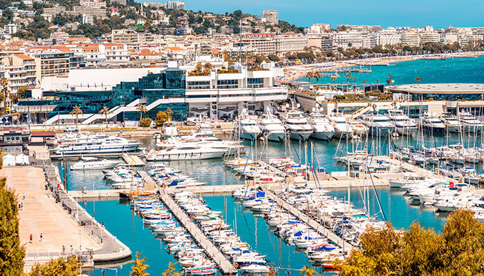 A scenic view of the Cannes marina filled with luxury yachts and clear blue waters, perfect for a south of France vacation.