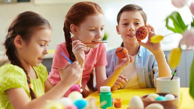 Children painting colorful Easter eggs at a table — one of the most creative and fun easter activities for kids at home.