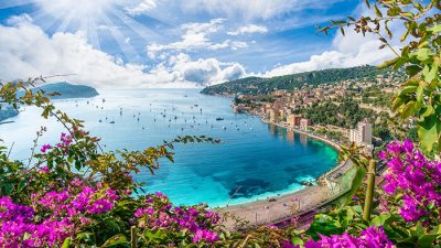 Scenic coastal view of the South of France with turquoise water, blooming flowers, and sunny skies — a perfect South of France vacation destination.