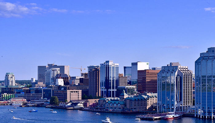 Halifax waterfront skyline with boats sailing in the harbor under clear blue skies — a top coastal city in eastern Canada.