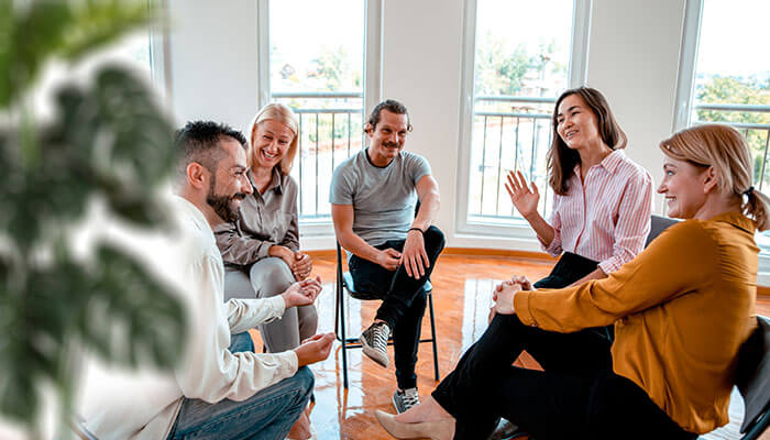 Colleagues sitting in a circle during a casual team discussion, sharing icebreaker questions to build rapport and create a positive atmosphere.