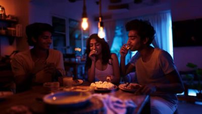 Friends enjoying late night snacks together under warm lighting, sharing food and laughter in a cozy kitchen setting.