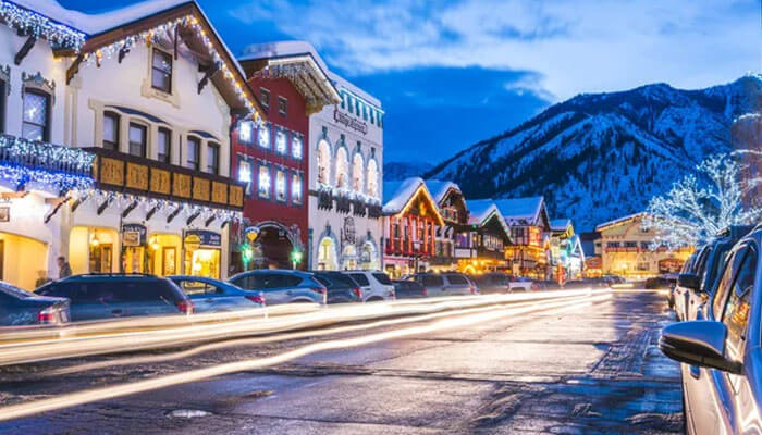 Charming winter evening view of Leavenworth, Washington, with Bavarian-style buildings, festive lights, and snow-covered mountains in the background.