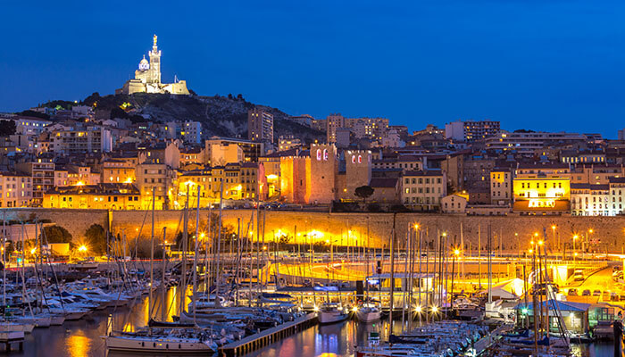 The illuminated harbor of Marseille at night with boats and historic buildings