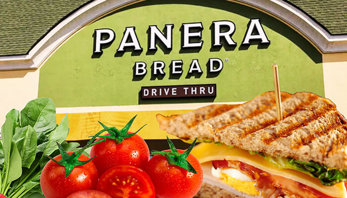 Panera Bread drive-thru sign with fresh tomatoes, spinach, and a grilled sandwich in the foreground — representing the restaurant’s fresh and healthy food offerings.
