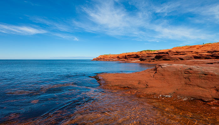 Red sandstone cliffs and calm blue waters along the coast of Prince Edward Island — one of Canada’s most beautiful beaches.