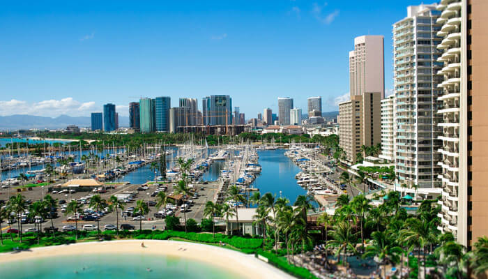 A scenic view of San Diego, California, showcasing the downtown skyline, marina filled with boats, and a sandy beach bordered by palm trees — capturing the city’s coastal charm and modern architecture.