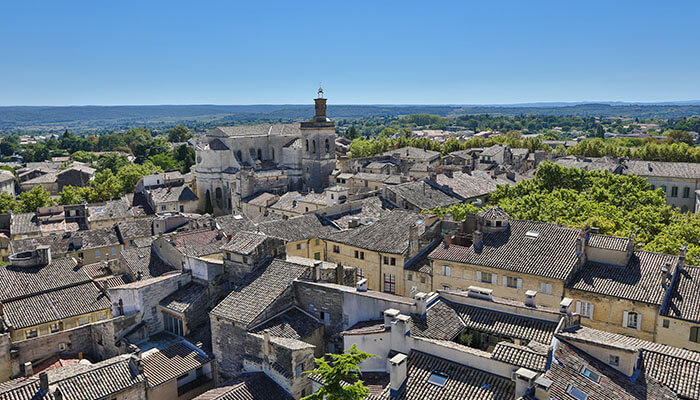 A panoramic view of Uzès with its rustic rooftops and historic church under clear skies, a charming destination for a south of France vacation.