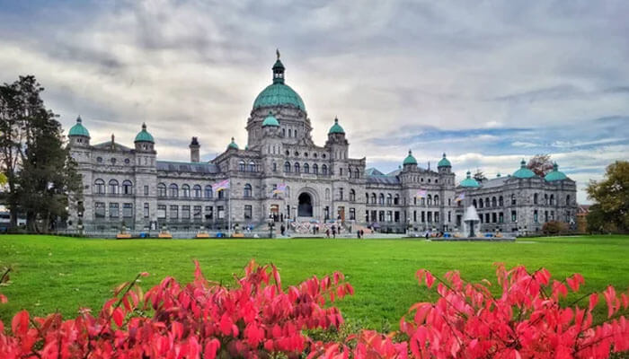 Victoria’s historic Parliament Building with green domes and colorful flowers in foreground — a popular landmark in British Columbia.