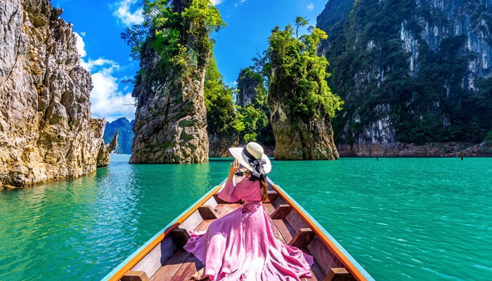Photography and Sightseeing - Food Fun Trip - FoodFunTrip A woman enjoying a boat ride through the serene waters of James Bond Island, Thailand, surrounded by towering limestone cliffs and lush greenery