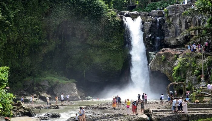Tegenungan Waterfall Visits and Reviews - Food Fun Trip - FoodFunTrip Tourists enjoying the scenic view of Tegenungan Waterfall in Bali, with lush greenery and mist rising from the base