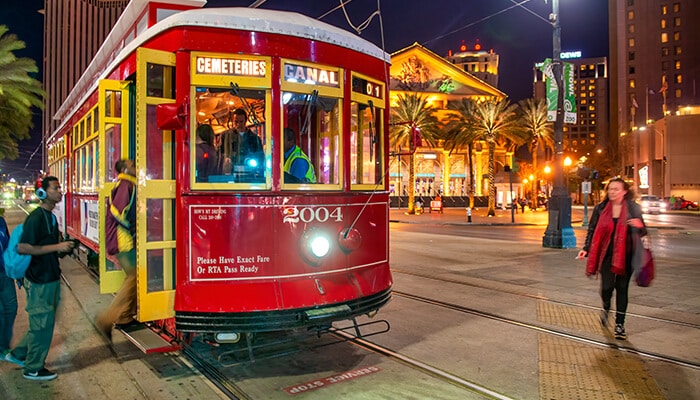 Ride the St Charles Streetcar - Food Fun Trip - FoodFunTrip A vibrant red streetcar in New Orleans at night, offering a unique way to explore the city and one of the best things to do in New Orleans
