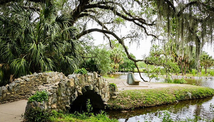 Visit City Park - Food Fun Trip - FoodFunTrip A scenic stone bridge in a park in New Orleans, offering a peaceful spot for visitors to relax and enjoy the greenery