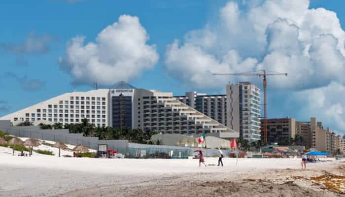 Iberostar Selection Cancun - Food Fun Trip - FoodFunTrip Beachfront view of Cancun all-inclusive resort with white sand beach, hotel buildings, and blue sky
