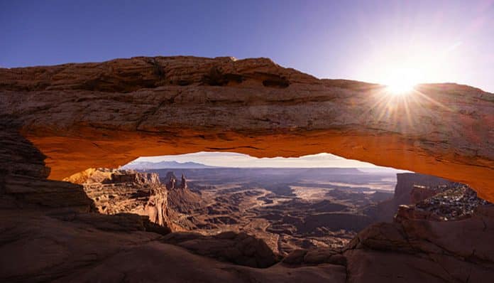 Sunrise over Canyonlands National Park in Utah, showcasing Mesa Arch framing expansive red rock canyons and rugged desert landscapes.