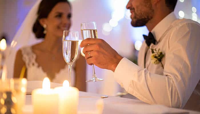 Choose Wines That Tell a Bit of Your Story - Food Fun Trip - FoodFunTrip Bride and groom clinking champagne flutes at a candlelit wedding reception.