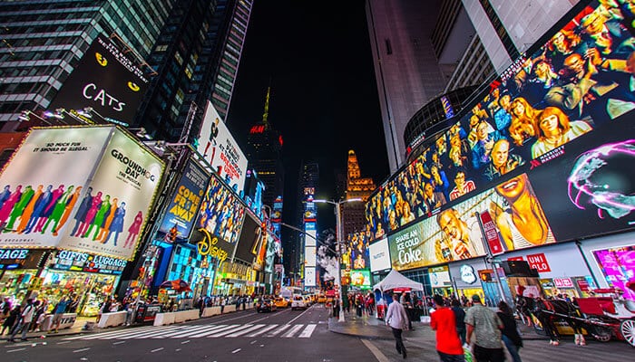 Etiquette of the Sidewalk - Food Fun Trip - FoodFunTrip Nighttime Times Square with towering neon billboards, crowds on the street, and taxis nearby.
