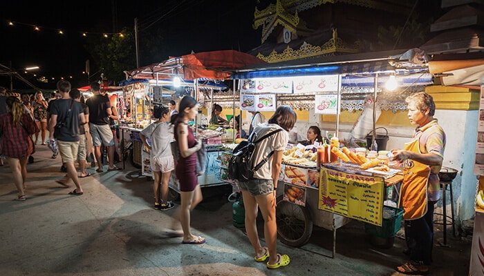 Spend Saturday in clusters - Food Fun Trip - FoodFunTrip Night market at night with food stalls, customers queuing and vendors cooking under string lights in a busy outdoor market.