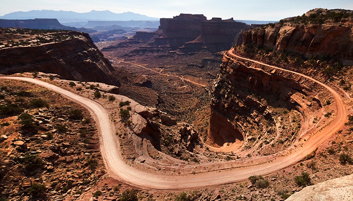 The White Rim Road - Food Fun Trip - FoodFunTrip Twisting dirt road over red rock cliffs at Canyonlands National Park, Utah, highlighting dramatic canyons, mesas, and rugged desert landscapes.