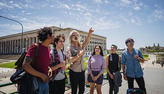Educational Tour group of students exploring a historic cultural landmark with a guide, promoting experiential learning, student travel programs, historical education, cultural awareness, and interactive academic experiences.