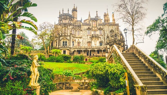 Quinta da Regaleira palace in Sintra, Portugal, showcasing Gothic architecture, ornate towers, lush gardens, and symbolic statues in a mystical setting.