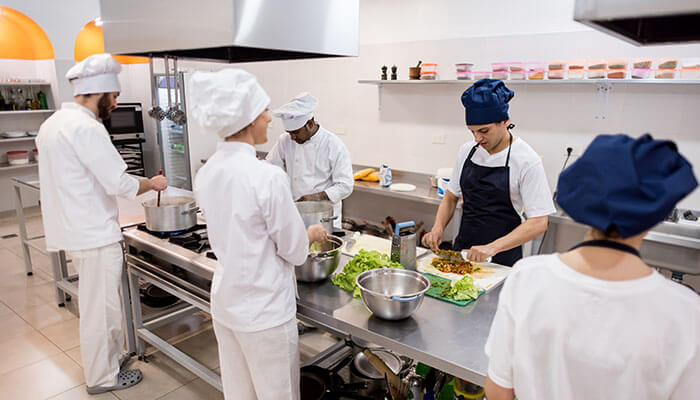 Staff Training and Operational Efficiency - Food Fun Trip - FoodFunTrip Professional chefs working in a commercial kitchen, showcasing the growth of food businesses from small-scale production to large-scale food preparation and catering operations.