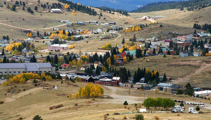 Cripple Creek KOA Holiday - Food Fun Trip - FoodFunTrip Best Places to Camp to See Fall Foliage featuring a scenic mountain community surrounded by rolling hills, evergreen forests, and golden aspen trees during the autumn season.