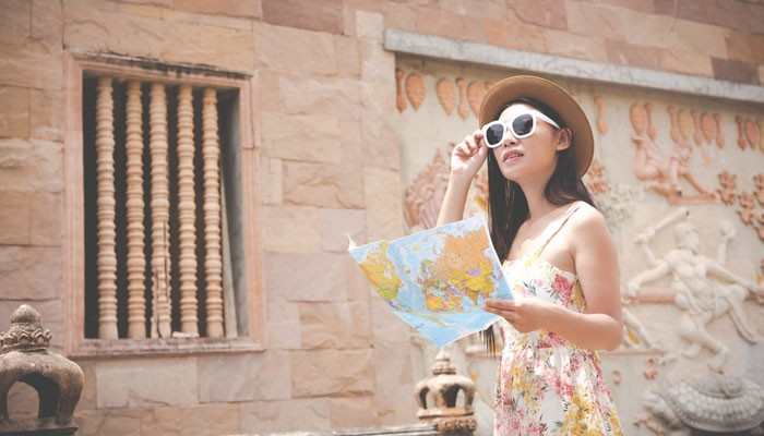 A Suggested Three- Day Jaipur Sightseeing Plan - Food Fun Trip - FoodFunTrip Sightseeing Guide LWMFTravel featuring a female tourist holding a travel map while exploring historic architecture with decorative stone carvings.