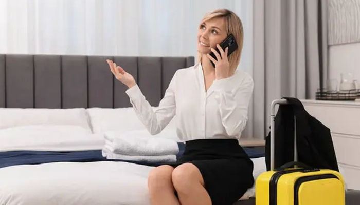 Confirm Essential Room Features Before Booking - Food Fun Trip - FoodFunTrip Hotels Travel Tweaks traveler calling hotel staff from a guest room to confirm room features, amenities, bed arrangements, and booking details before her stay.