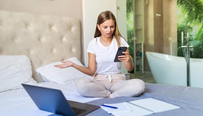 Verify Unexpected Payment Requests - Food Fun Trip - FoodFunTrip Hotels Travel Tweaks traveler checking a suspicious payment request on her phone in a hotel room while verifying booking and payment details online.